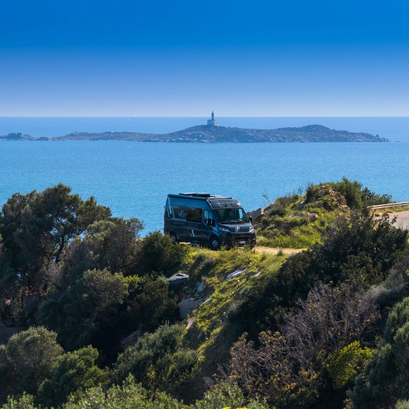 Scopri la Sardegna in van Camper parcheggiato su una scogliera con vista mare e faro sull'isola lontana