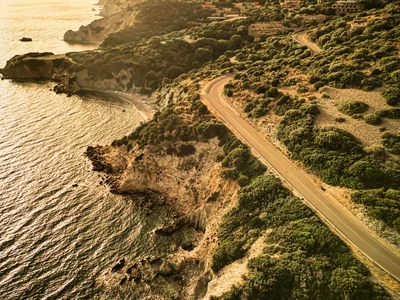 Scopri la Sardegna in van Strada costiera curva al tramonto con colline e mare