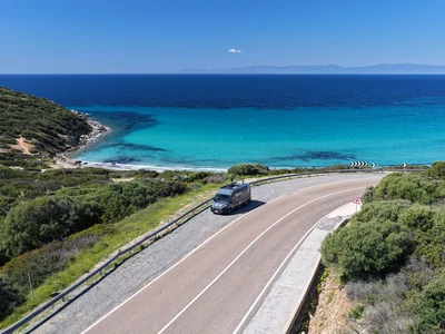 Scopri la Sardegna in van Strada costiera con furgone vicino al mare turchese e cielo sereno