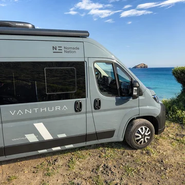Scopri la Sardegna in van Furgone da campeggio Vanthura vicino al mare con cielo azzurro e isola in lontananza