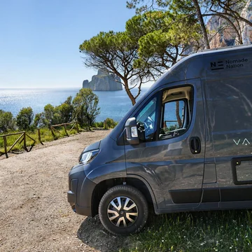 Scopri la Sardegna in van Furgone scuro parcheggiato su strada sterrata vista mare con alberi e scogliere